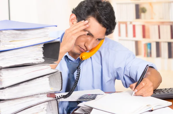 Jeune homme accablé stressé avec des piles de dossiers sur son bureau — Photo