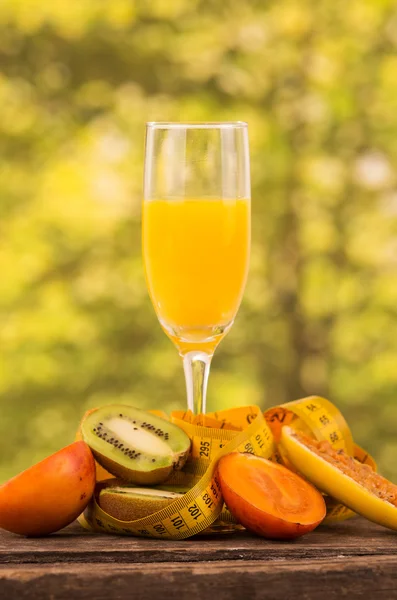 Vaso de jugo con kiwi, tomate de árbol y rodajas de plátano de maracuyá sobre una mesa de madera —  Fotos de Stock