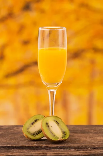 Glass of juice with kiwi slices on a wooden table — Stock Photo, Image