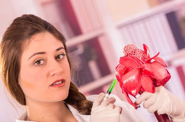 Beautiful female biologist experimenting with red flower — Stock Photo, Image