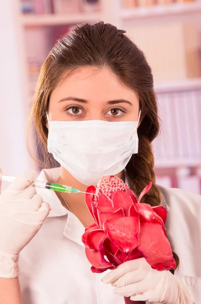 Beautiful female biologist experimenting with red flower — Stock Photo, Image