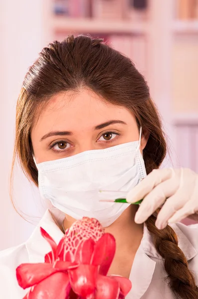 Beautiful female biologist experimenting with red flower — Stock Photo, Image