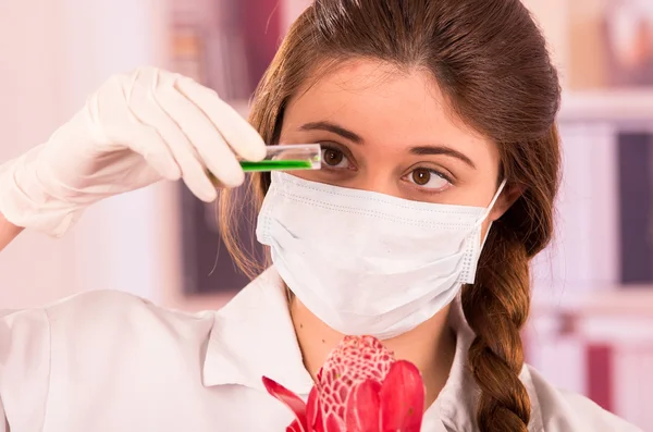 Bela bióloga feminina experimentando com flor vermelha — Fotografia de Stock