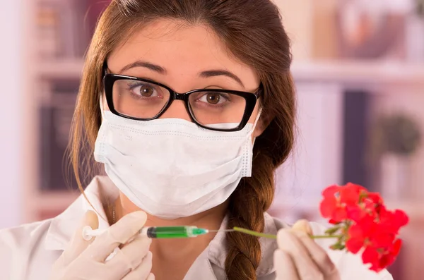 Young female biologist experimenting with red flower — Stock Photo, Image