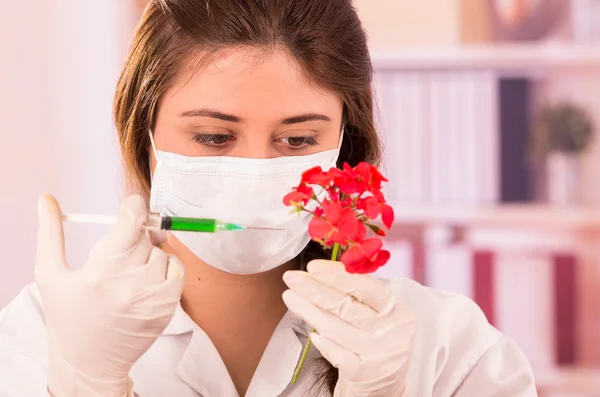 Young female biologist experimenting with red flower — Stock Photo, Image