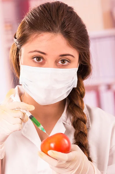 Joven bióloga inyectando jeringa en un tomate —  Fotos de Stock