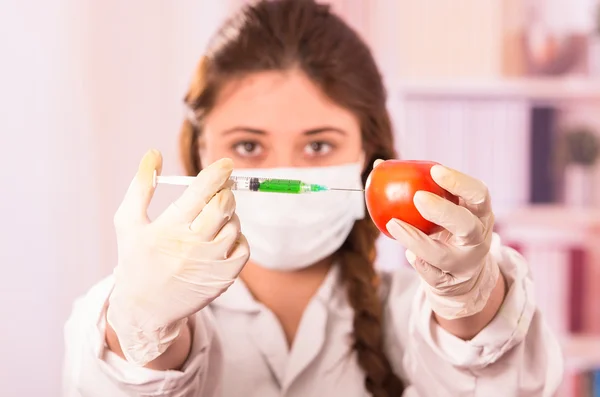 Young female biologist injecting syringe in a tomato — Stock Photo, Image