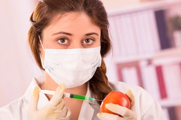 Joven bióloga inyectando jeringa en un tomate —  Fotos de Stock