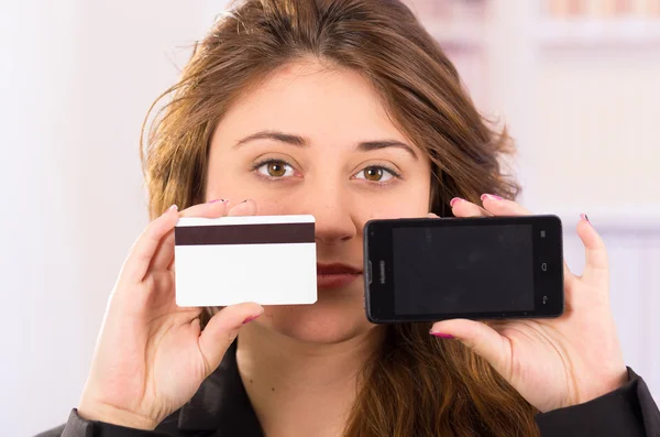 Moderna bela jovem segurando telefone celular e cartão de crédito — Fotografia de Stock