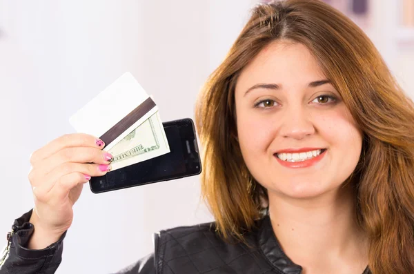 Mujer joven hermosa moderna sosteniendo el teléfono celular, dinero y tarjeta de crédito — Foto de Stock