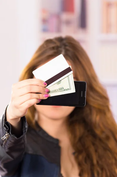 Mujer joven hermosa moderna sosteniendo el teléfono celular, dinero y tarjeta de crédito — Foto de Stock