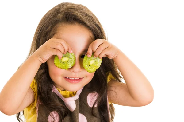 Linda niña preescolar sosteniendo rodajas de kiwi frente a sus ojos —  Fotos de Stock