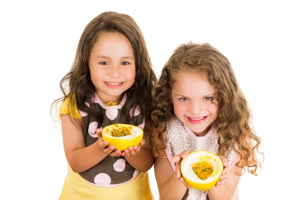 Cute little preschooler girls holding a cut open passion fruit — Stock Photo, Image