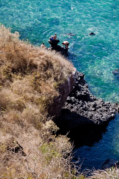 Niet-geïdentificeerde toeristen genieten van de oceaan met kristal duidelijk water en zwemmen zeeleeuwen in San Cristobal, Galapagos eilanden — Stockfoto