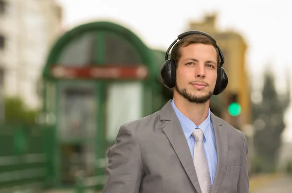 Joven elegante hombre guapo con auriculares en la ciudad — Foto de Stock