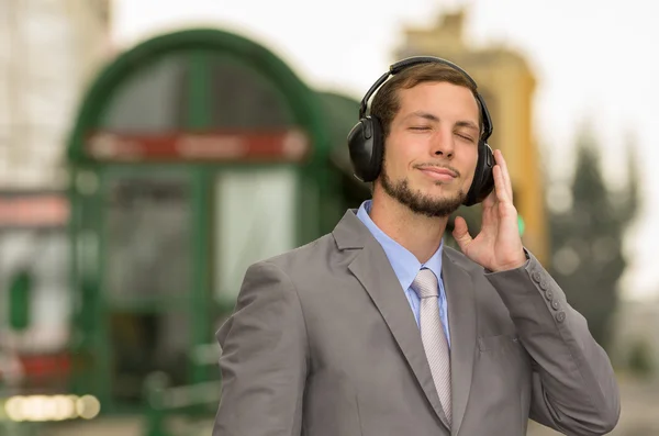 Joven elegante hombre guapo con auriculares en la ciudad — Foto de Stock
