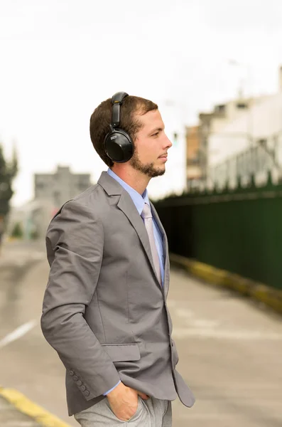 Joven elegante hombre guapo con auriculares en la ciudad — Foto de Stock