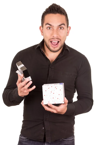 Charming young man holding a gift box looking surprised — Stock Photo, Image
