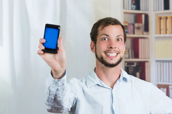 Młody człowiek szczęśliwy, trzymając jego telefon komórkowy i pokazywanie ekranu — Zdjęcie stockowe