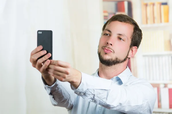 Attraktiv ung man använder mobiltelefon för att ta en selfie — Stockfoto