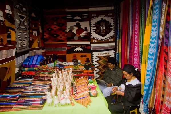 Azonosítatlan őshonos pár színes textil istállóban tart, a népszerű piac Otavalo, Ecuador — Stock Fotó