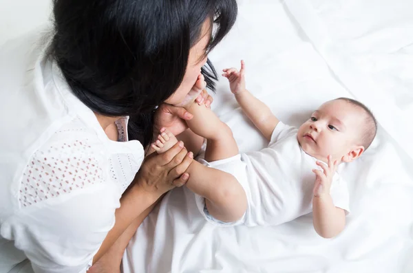 Liefdevolle jonge moeder kussen babys voet — Stockfoto