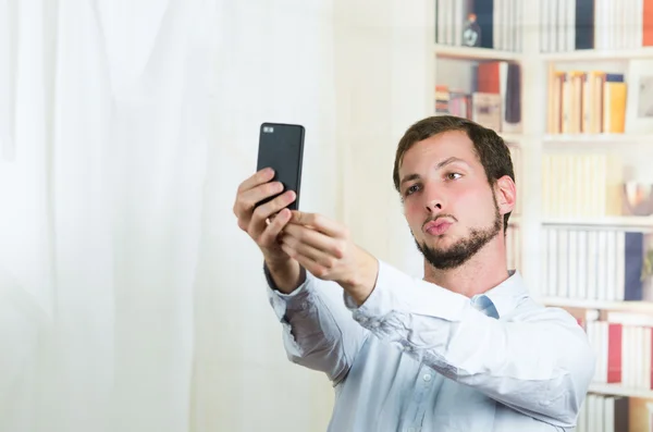 Attractive young man using cell phone to take a selfie — Stock Photo, Image
