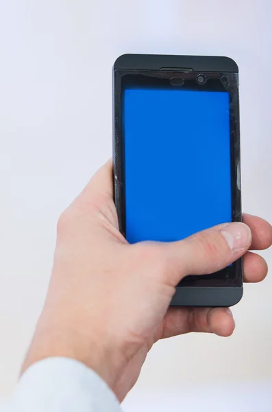 Mão mans segurando telefone celular com tela azul vazia — Fotografia de Stock