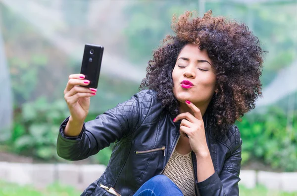 Exotic beautiful young girl taking a selfie sitting in the garden — Stock Photo, Image