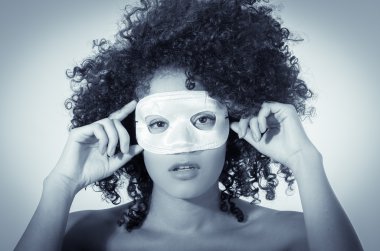 bir maske takarak kısa kıvırcık siyah saçlı genç kadın