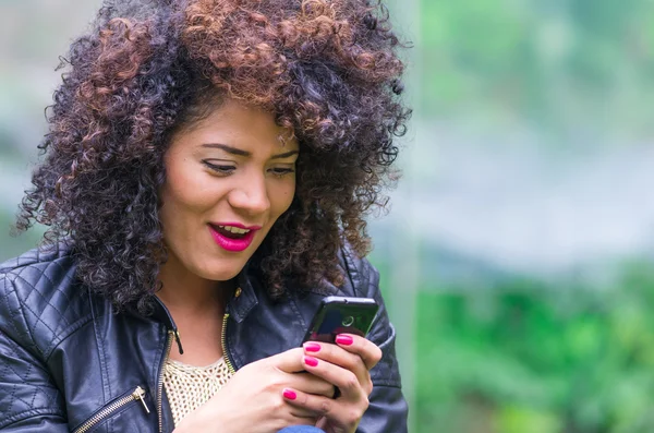 Exotique belle jeune fille en utilisant téléphone cellulaire assis dans le jardin — Photo