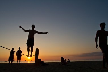 Genç adam Manabi, Ekvator bir plajda slackline Dengeleme silüeti