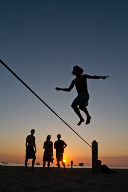 Genç adam Manabi, Ekvator bir plajda slackline Dengeleme silüeti