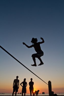 Genç adam Manabi, Ekvator bir plajda slackline Dengeleme silüeti