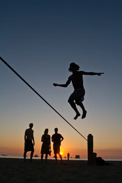 Silueta de joven balanceándose en slackline en una playa en Manabí, Ecuador — Foto de Stock