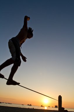 Genç adam Manabi, Ekvator bir plajda slackline Dengeleme silüeti
