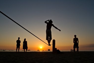 Genç adam Manabi, Ekvator bir plajda slackline Dengeleme silüeti
