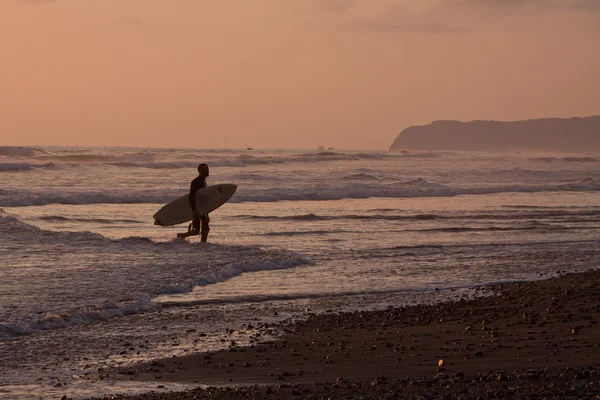 Niet-geïdentificeerde toeristische surfer genieten van de zee tijdens zonsondergang, Puerto Lopez, Ecuador — Stockfoto
