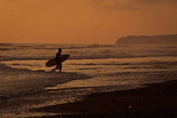 Silhouet van toeristische surfer genieten van de zee tijdens zonsondergang, Manabi, Ecuador — Stockfoto