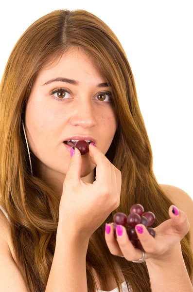 Beautiful young supersticious woman eating grapes — Stock Photo, Image