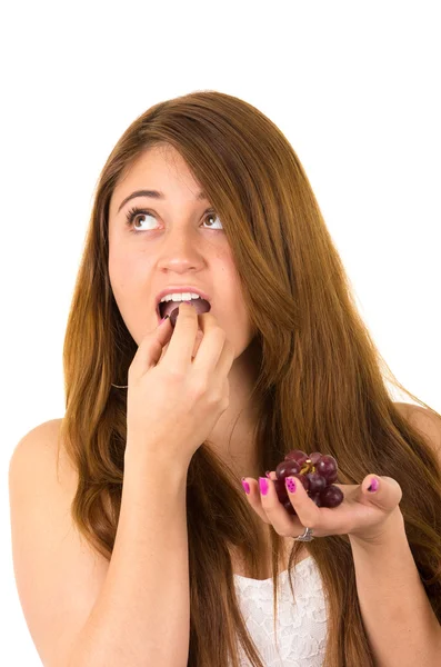 Beautiful young supersticious woman eating grapes — Stock Photo, Image