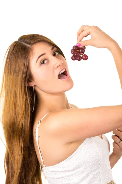 Beautiful young supersticious woman eating grapes — Stock Photo, Image