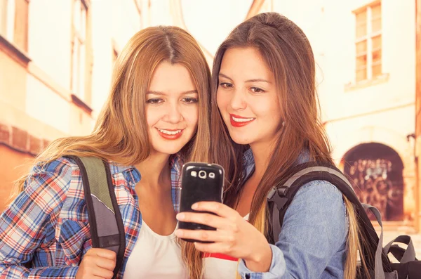 Cute young fashionable girls using cell phone — Stock Photo, Image