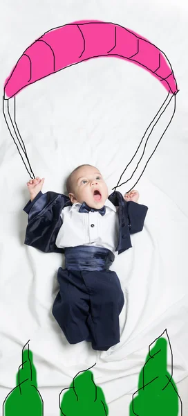 Cute baby boy decorated falling in a parachute — Stock Photo, Image