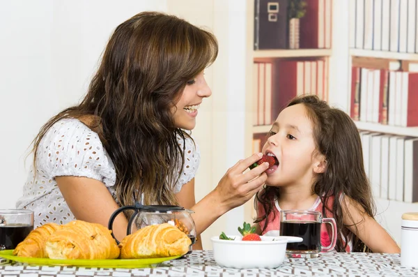 Beautiful young mom feeding fruit to cute little girl — Stock Photo, Image