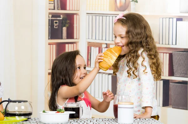 Cute little girl feeding bread to her sister — Stock Photo, Image