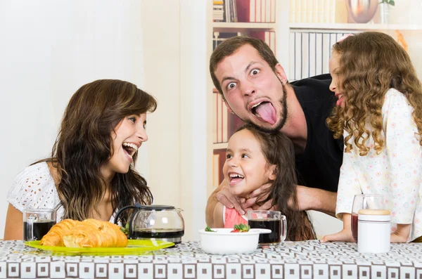 Playful family with two girls eating breakfast — Stock Photo, Image