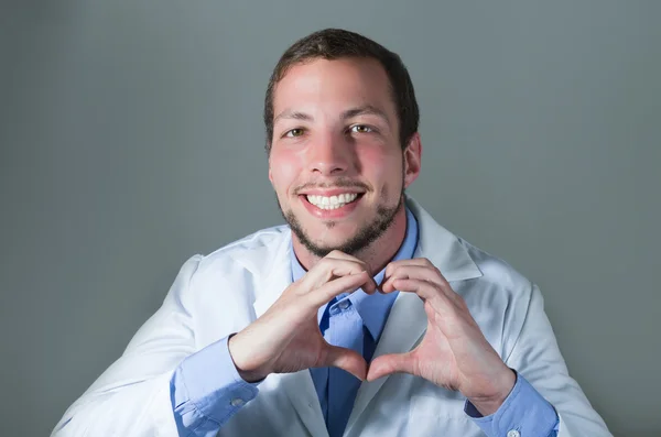 Primer plano retrato de guapo joven médico haciendo un corazón con las manos — Foto de Stock