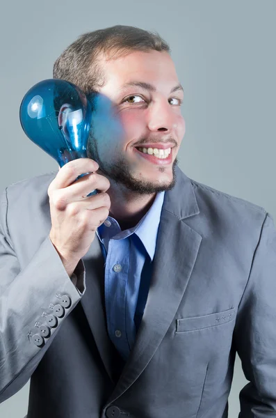 Bonito jovem inteligente segurando uma lâmpada azul — Fotografia de Stock