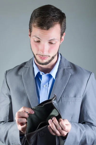 Retrato de un joven guapo sosteniendo la cartera vacía — Foto de Stock